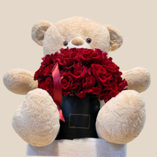 Teddy bear hugging black box filled with red roses – Valentine’s flower delivery Lebanon.