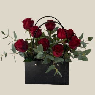 Red roses and eucalyptus in luxury black handbag – modern floral arrangement for Valentine’s delivery in Lebanon.